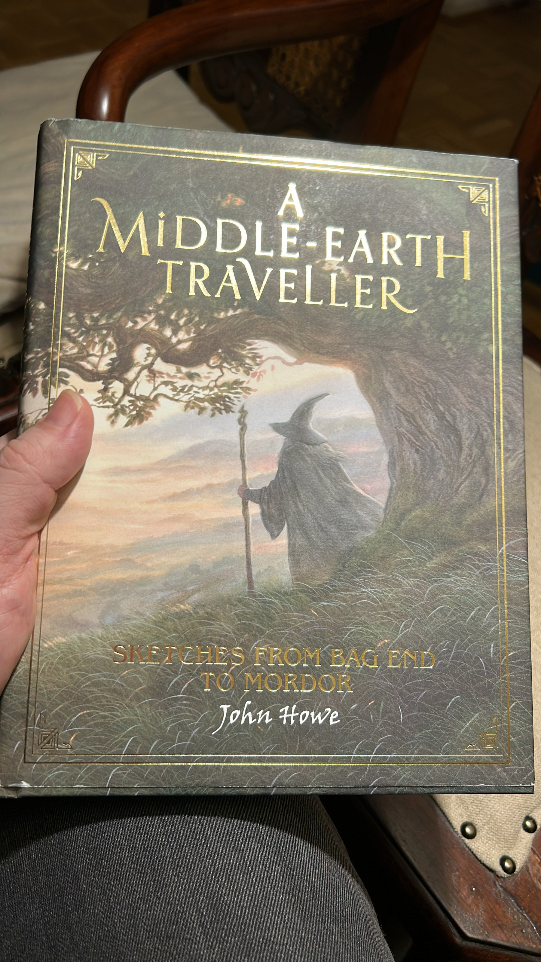 Cover des Buches mit Goldlettering zeigt Gandalfs Rücken unter einem Baum auf einem grünem Grashügel.